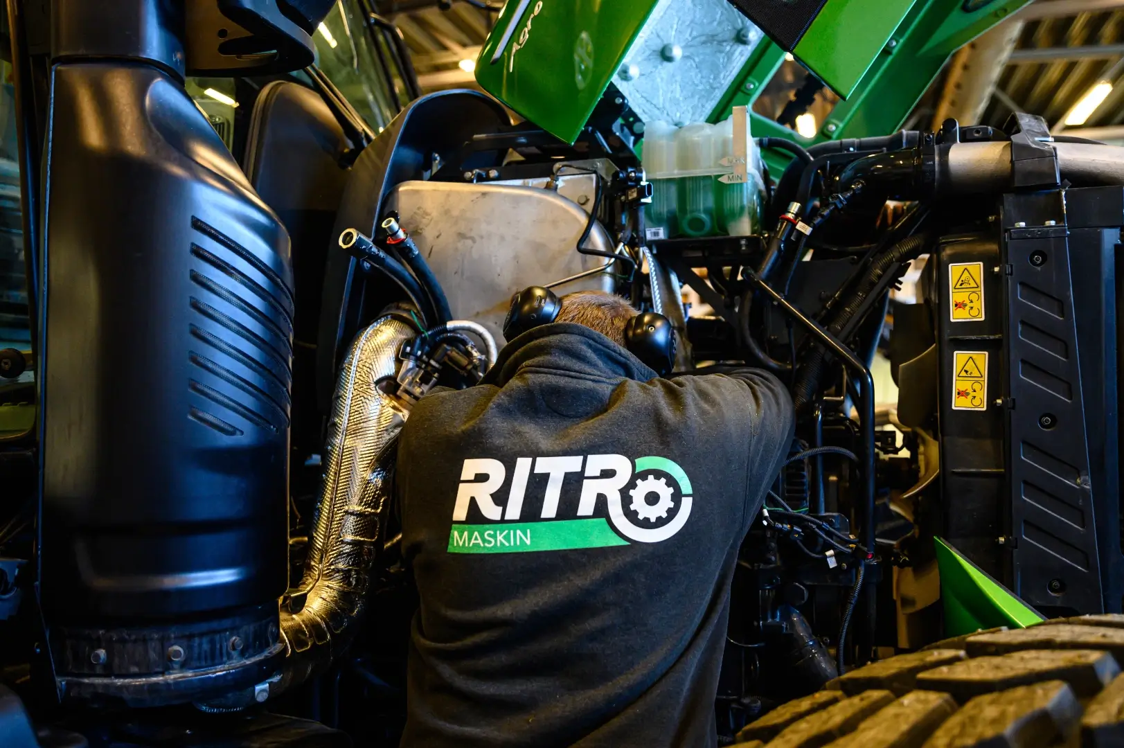 Mekaniker jobber på en Deutz-Fahr med ryggen til.