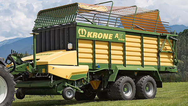 KRONE AX høstevogn med løsrivbar hakkemaskin montert foran, vist fra siden med fullastet høy og grønne slåkurver på toppen.