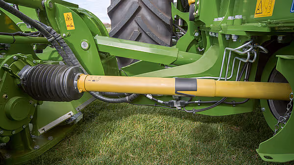 Nærbilde av hydraulisk drivaksel på KRONE Big M 450 slåmaskin. Den gule akselen forbinder traktoren med slåmaskinen for kraftoverføring.