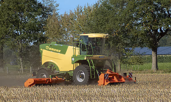 Krone Big M 450 selvgående slåmaskin i arbeid på kornstubber. Maskinen har oransje slåtteredskap foran og arbeider på avhøstet åker.