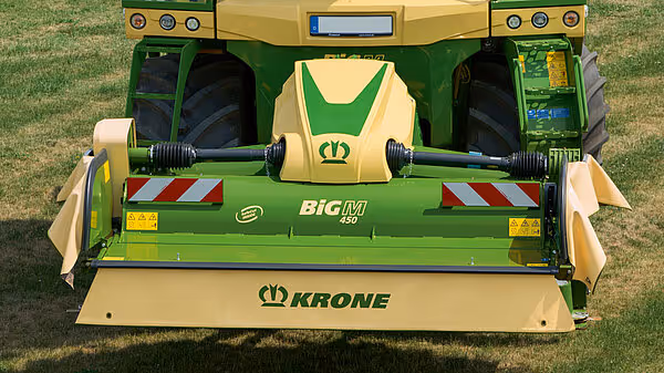 Nærbilde av Krone Big M 450 slåmaskin bakfra med utslått slåtteredskap. Maskinen viser den karakteristiske gul-grønne fargen og model 450-merking.