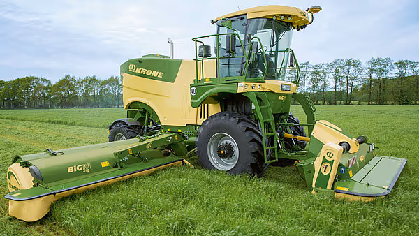 KRONE Big M 450 slåmaskin på grønt grasareal. Maskinen har gul og grønn farge med bred slåttemekanisme foran.