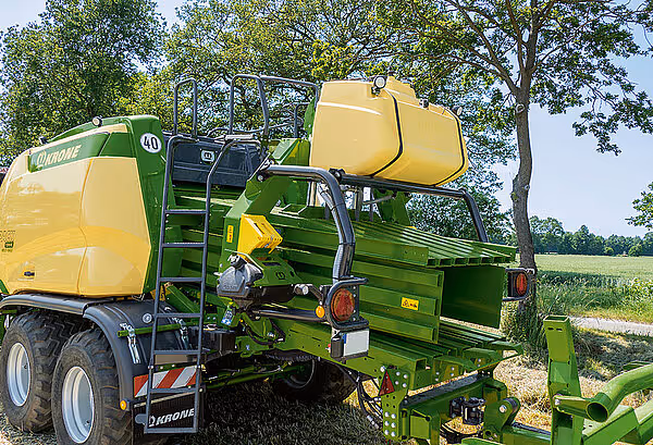 Bakside av en Krone BigPack storballpresse som viser hydraulikksystemet og bindeanordningen for plastsnor under drift.