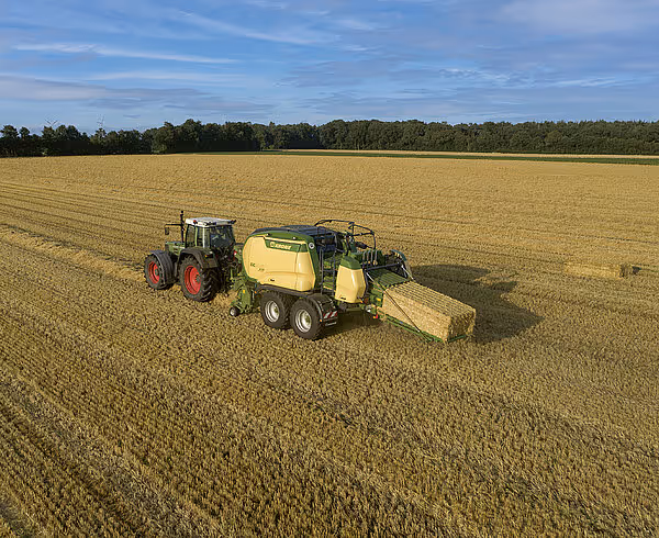 Luftfoto av Fendt traktor med Krone BigPack storballepress i arbeid på stor stubbeåker.