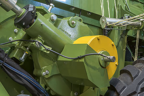 Detaljbilde av KRONE Big Pack HDP-II sin grønne drivmekanisme med gul deksel og hydrauliske komponenter.