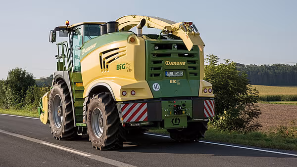 Krone BiG X finsnitter kjører på landevei med påmontert pick-up-aggregat.