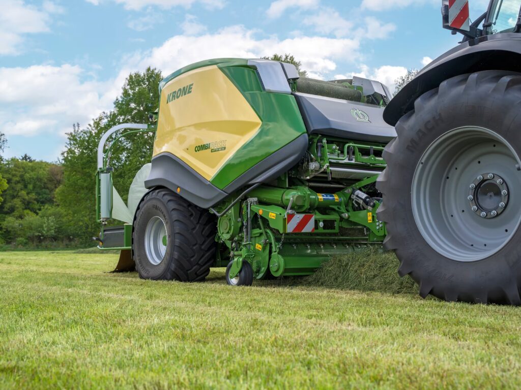 Nærbilde av pickup og snitteenhet på KRONE CombiPack HDP CV 165 XC som samler opp gras på eng.