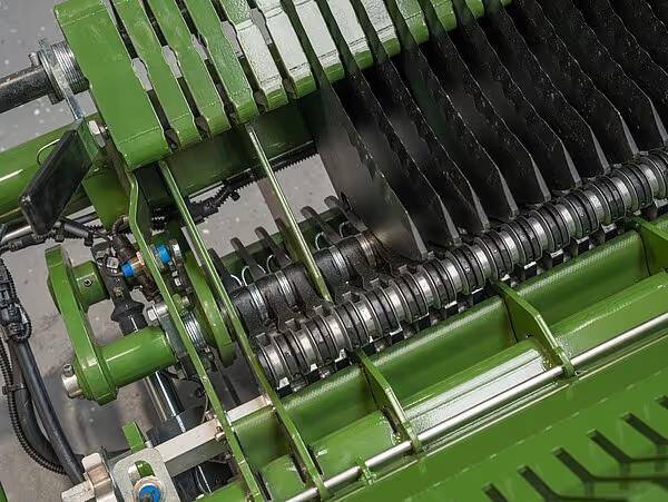 Innvendig bilde av en roterende sylinder med mange skarpe metallskiver eller kniver arrangert i rekker. Dette er trolig en del av jordbearbeidingsmekanismen.