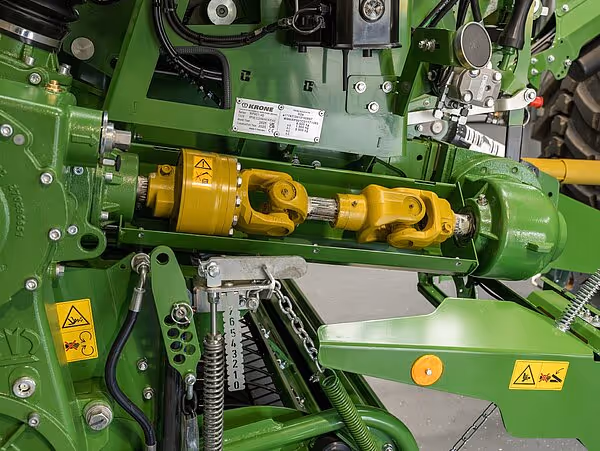 Detaljbilde av den gule kraftoverføringen og drivakselsystemet på KRONE CombiPack HDP ballepress.