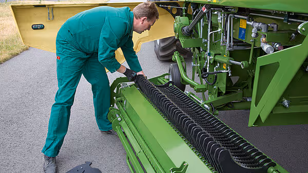 Servicetekniker inspiserer og justerer den sorte såkjedetransmisjonslisten på KRONE MX såmaskinen.