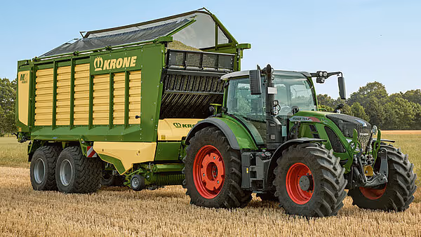 Fendt traktor med grønn og gul Krone MX silofôrvogn koblet på et stubbefelt.