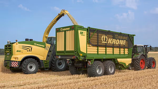 Gul Krone Bio meieriskipsmaskin med utrekkbar arm fyller grønn og gul Krone MX vogn under silering.