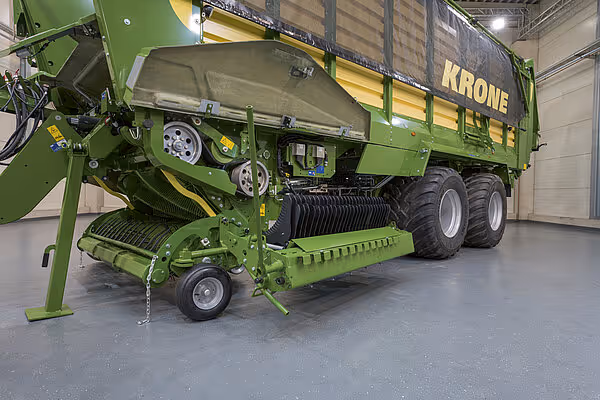 KRONE RX Tabs 24 silofyllingsmaskin med grønn farge, montert på stort transportvogn med gul striper og KRONE-logo i lagerhall.
