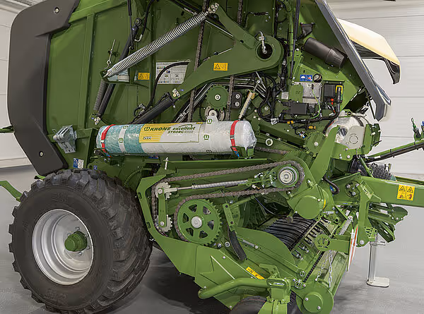 Sidevisning av Krone VariPack Pro rundballpresse som viser hydraulikksylinder, nettbeholder og den grønne maskinens konstruksjon.