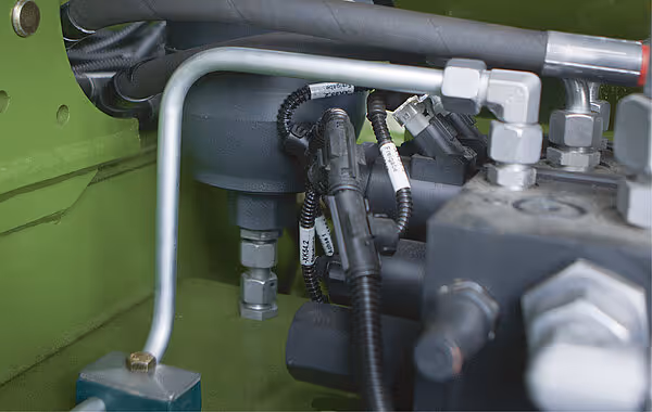 Hydraulikkontroll og kabelkoplinger på KRONE ZX høstmaskin, med sorte slanger og hvite stikkontakter montert på grønn ramme.