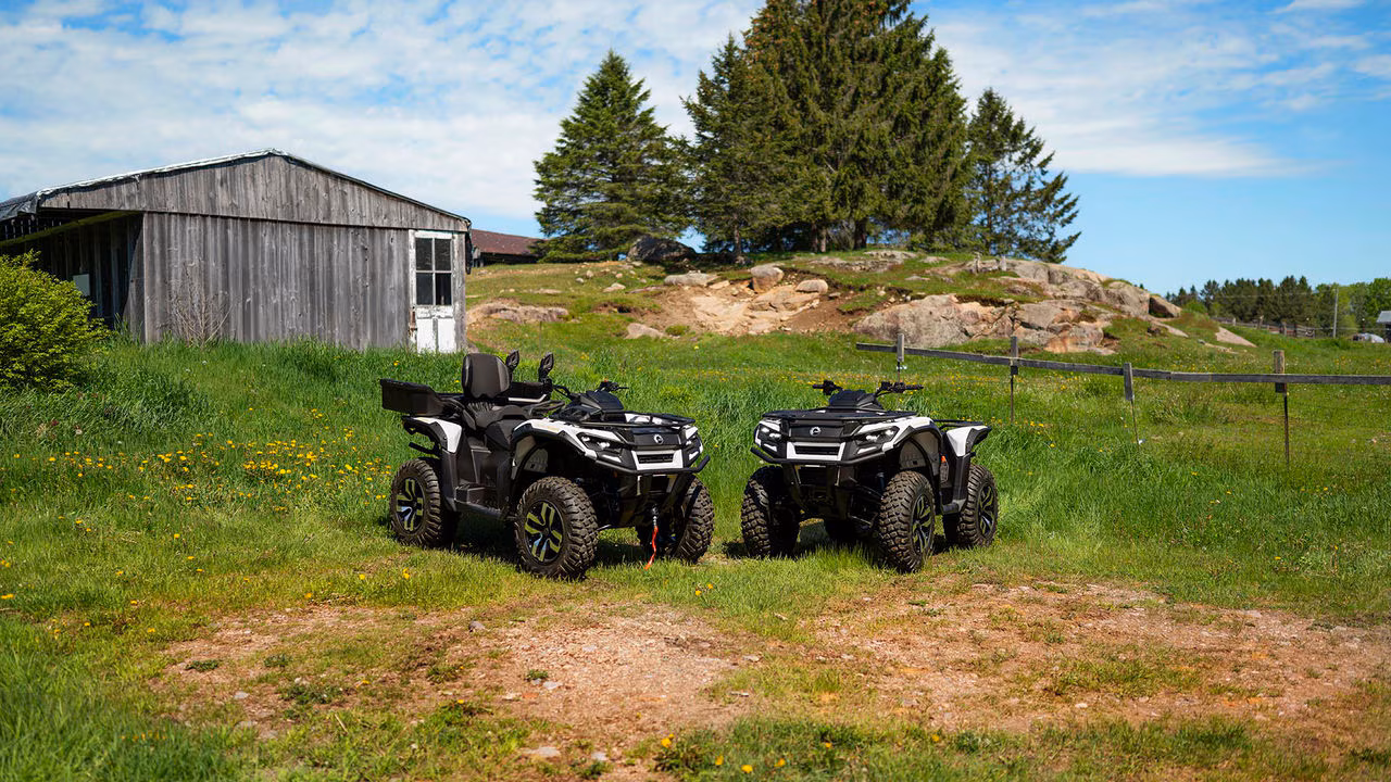 To Can-Am Outlander Electric ATV-er parkert i gresset.